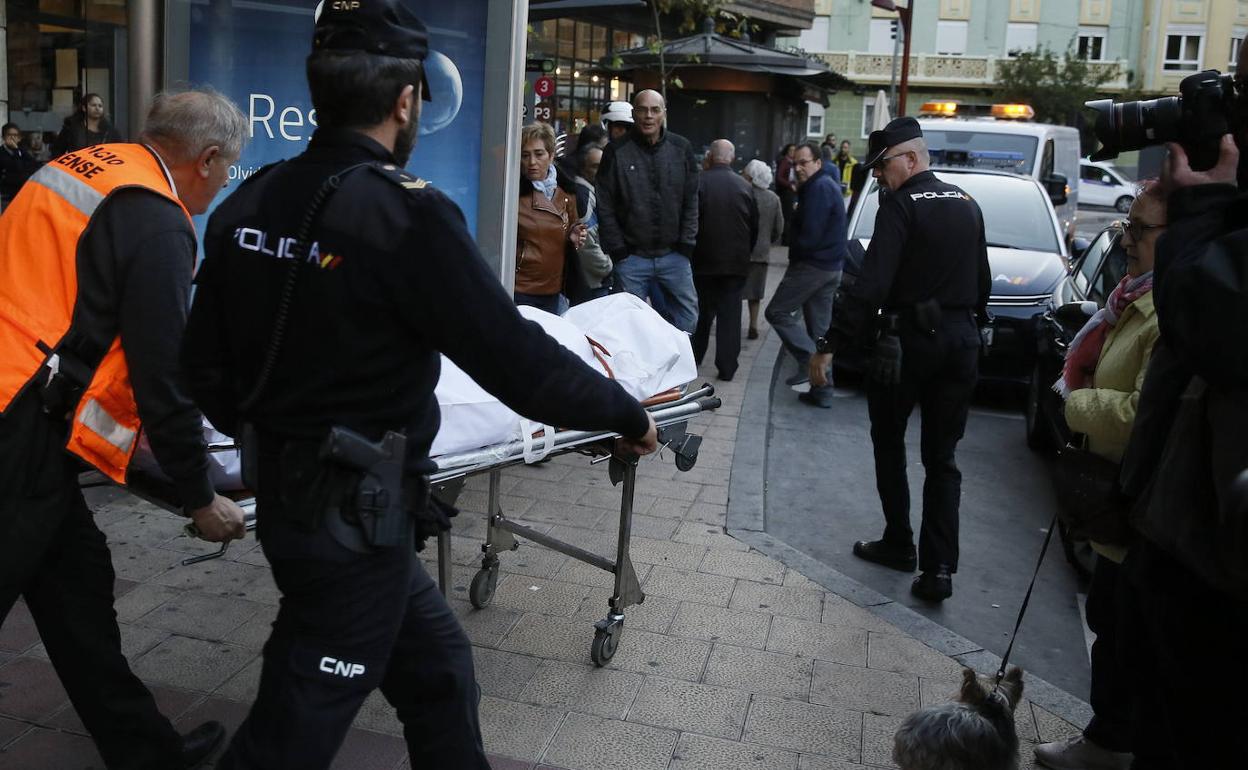 Agentes de Policía junto a operarios del servicio forense trasladan el cadáver de la mujer en la Plaza Circular de Valladolid. / Gabriel Villamil