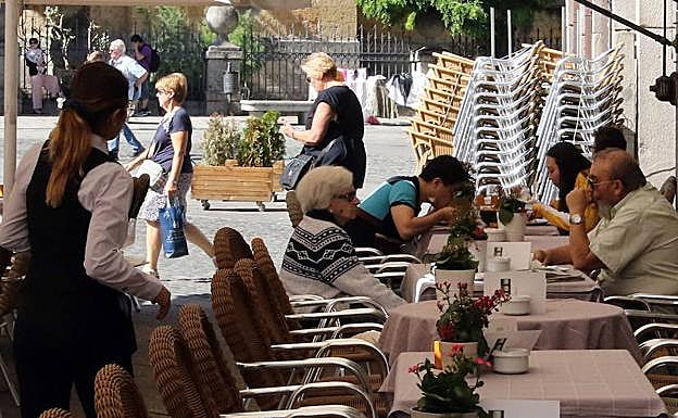 Una camarera atiende unas mesas en una céntrica terraza de Segovia.