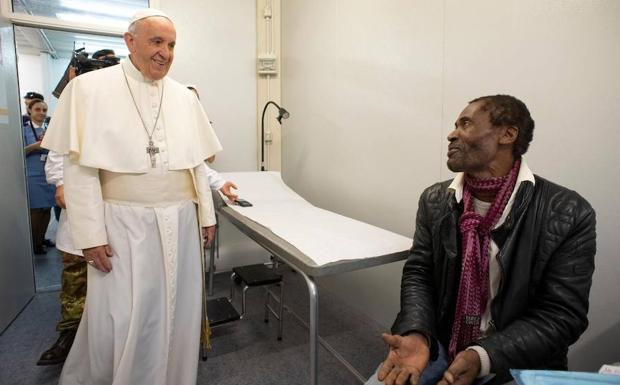 El papa Francisco (i) conversa con un paciente durante su visita sorpresa al ambulatorio que ha instalado el Vaticano para atender a personas vulnerables y sin recursos. 