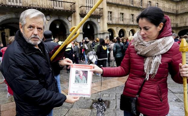 Dos voluntarios sostienen un cartel con la imagen del desaparecido. 
