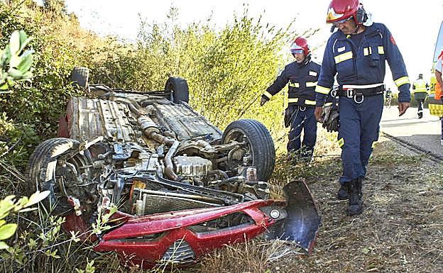 Dos bomberos de Ciudad Rodrigo examinan un coche accidentado en la N-620.