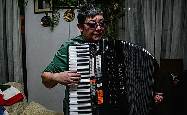 María José Castaño toca el acordeón en su casa. A la izquierda, hojas con canciones escritas en braille. 