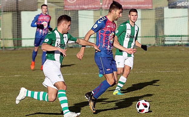 Álex Conde avanza con el balón perseguido por un jugador de la Cebrereña.