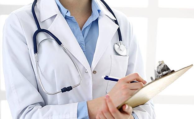 Una médico toma notas en la vista a un paciente. 