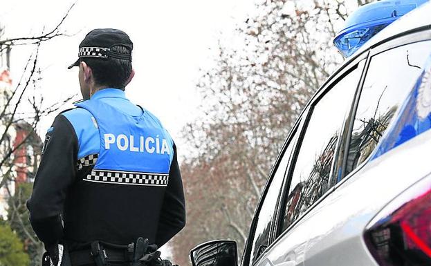 Un agente de la Policía Local de Valladolid junto a su vehículo.