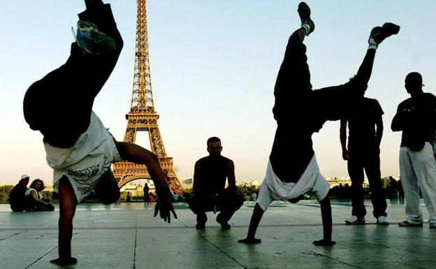 Un grupo de jovenes bailan en frente de la Torre Eiffel en París.