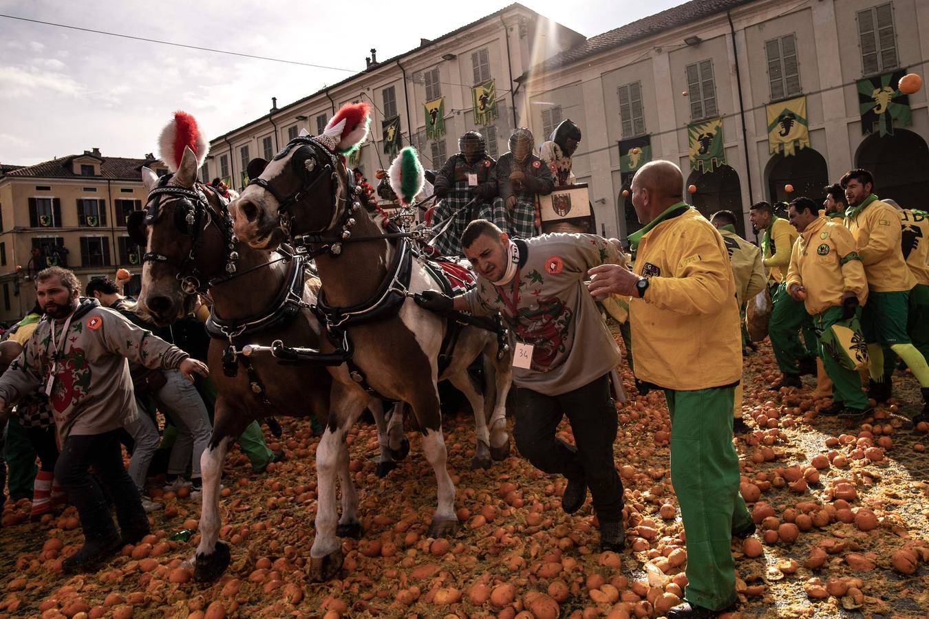 El histórico Carnaval de Ivrea, localidad de Piamonte en la provincia de Turín, representa la guerra civil entre el pueblo y las tropas reales napoleónicas, el día después de la muerte del odiado tirano Raineri de Bramante a manos de la 'Mugnaia' | Los equipos de lanzadores de naranjas a pie (el pueblo) defienden sus plazas de los lanzadores de los carros (el Estado Mayor Napoleónico) a golpe de naranja