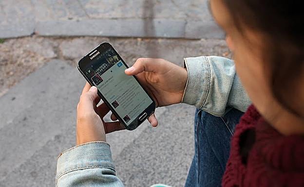 Una joven hace uso de las redes sociales en su teléfono móvil.