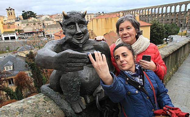 Dos mujeres se hacen un 'selfie' con el diablillo de la cuesta de San Juan en Segovia. 