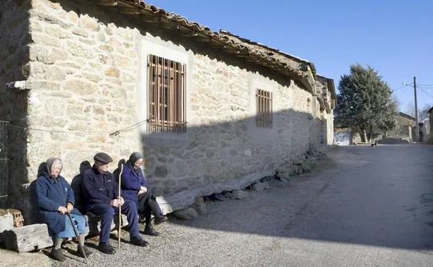 Tres vecinos charlan sentados en una calle de la localidad zamorana de Manzanal de los Infantes
