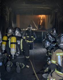 Imagen secundaria 2 - El contenedor contiene una zona de combustión sobreelevada para controlar los gases. Bajo ella se ha colocado ladrillo refractario para que la instalación aguante más tiempo, ya que se alcanzan temperaturas de casi 600º. Colocarse bien el equipamiento es clave, porque la simulación, aunque controlada, es con fuego real. A la derecha, momento en que el instructor explica cómo comienza el fuego. Se pretende que sepan distinguir las diferentes fases por las que evoluciona un incendio desde su inicio.
