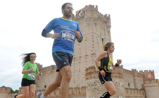 Participantes en una prueba deportiva corren delante del castillo de la Mota de Medina.