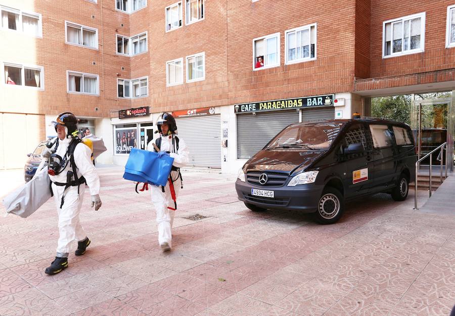 Los bomberos salen del bloque de viviendas después de sacar al fallecido de su vivienda.