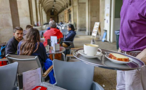 Un camarero sirve el desayuno en una terraza.