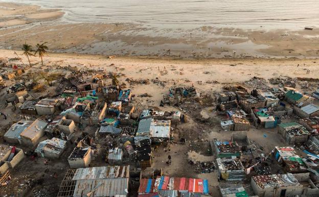 Imagen principal - Arriba, estado en el que quedó el barrio de Praia Nova, en Beira, tras el paso del ciclón. Abajo, reparto de material solidario y destrozos en la zona. 
