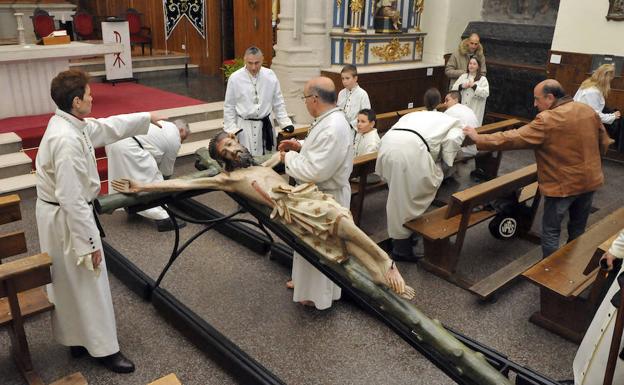 Los cofrades del Descendimiento secan la talla del Cristo en la iglesia de San Miguel. 