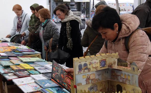 Varias mujeres examinan los libros expuestos en la Plaza Mayor.