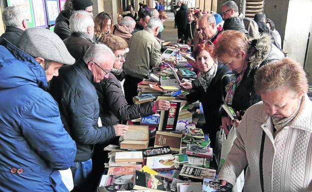 Varias personas participan en la cadena de intercambio de libros en los soportales de la Plaza Mayor. 