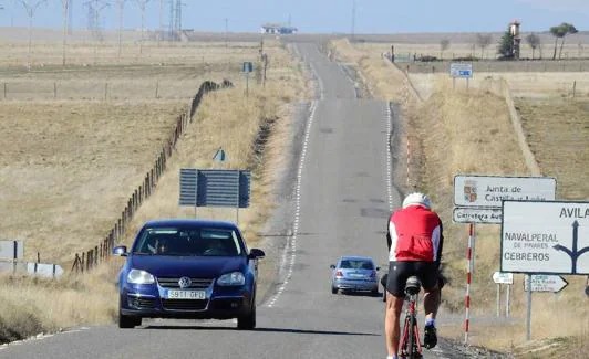 Ciclistas y coches circulan por la carretera autonómica SG-500 en dirección a Ávila por su prolongación, la AV-500. 