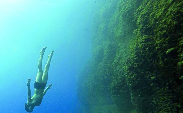 Un joven bucea en las profundidades de un lago. 