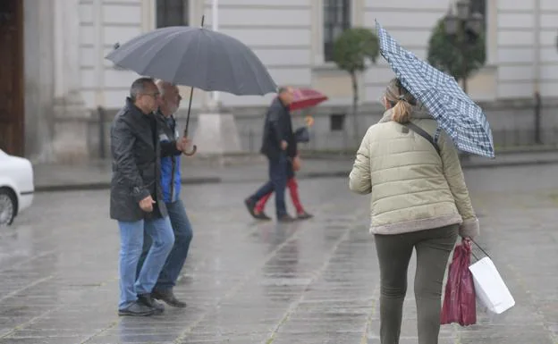 Varias personas se protegen de una llovizna en el mes de abril en la zona de San Pablo de Valladolid. 