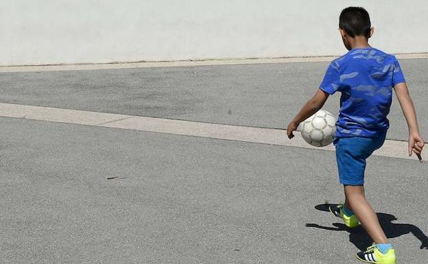 Un niño juega con un balón de fútbol en un patio. 