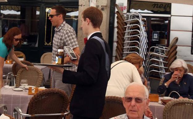 Un camarero sirve unas mesas en una terraza de la Plaza Mayor de Segovia. 