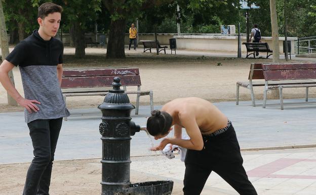 Dos jóvenes beben agua en una fuente de Las Moreras. 