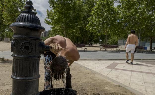 Un joven se refresca en una fuente en el entorno de la playa de Las Moreras.