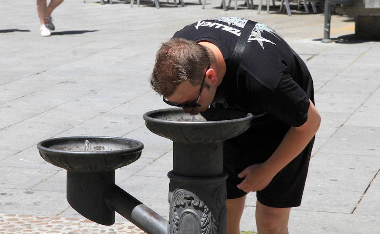 Un hombre bebe agua de una fuente en la capital. 