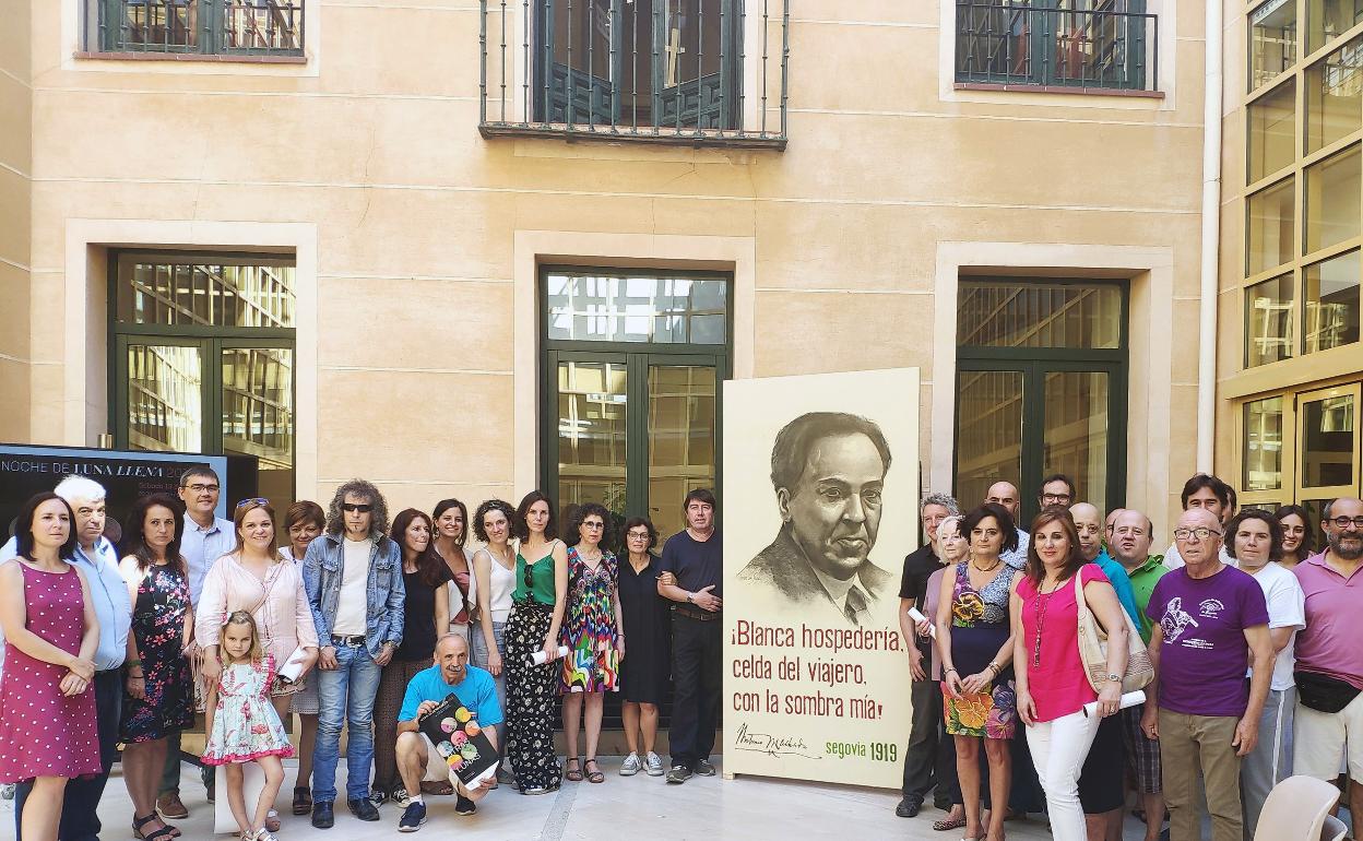 Asistentes a la presentación del programa de este año posan en el patio del Ayuntamiento junto a un cartel con la imagen de Antonio Machado