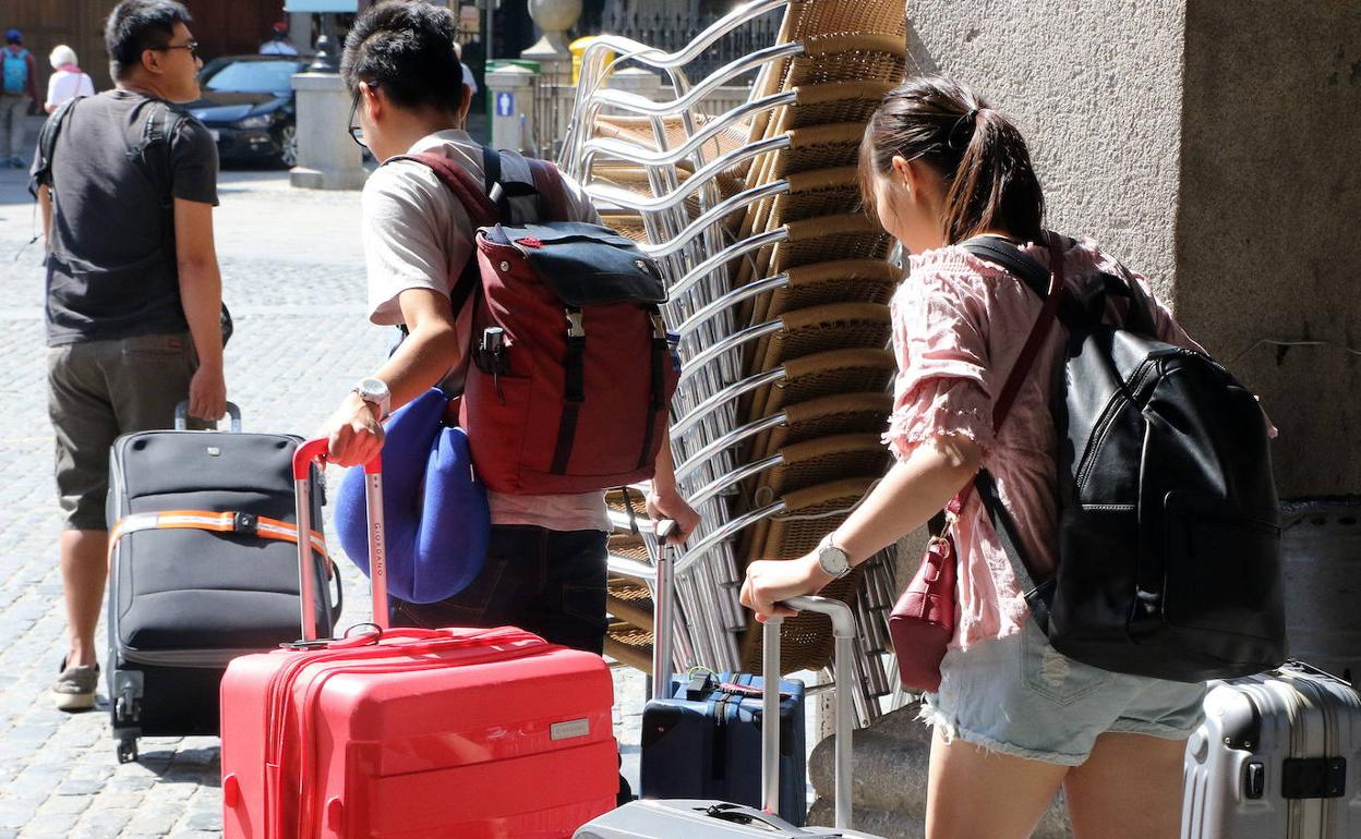 Turistas extranjeros arrastran sus maletas por el centro de Segovia. 