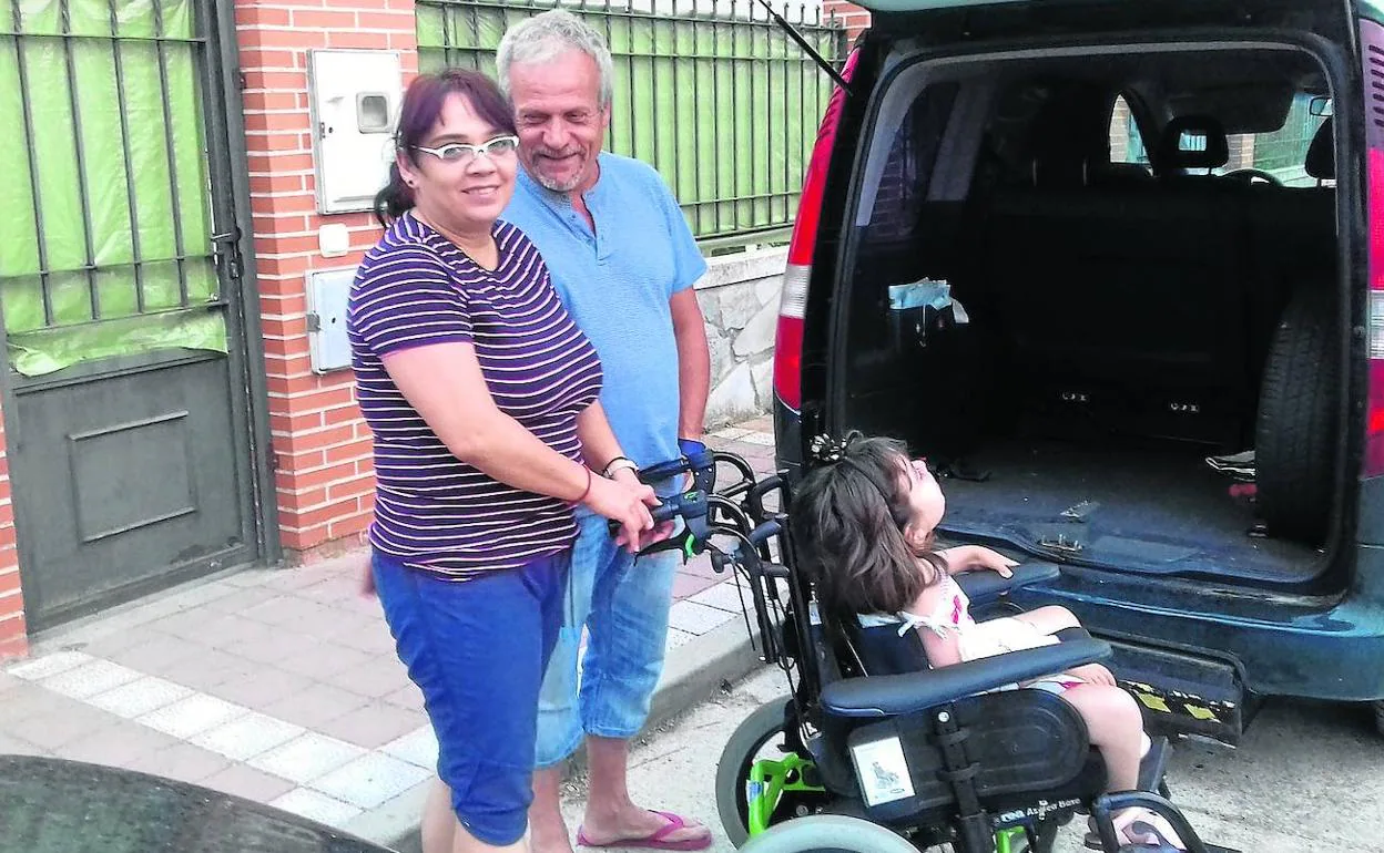 La pequeña Yanira, en su nueva silla de ruedas, acompañada por sus padres, Sonia y Luis Ángel. 