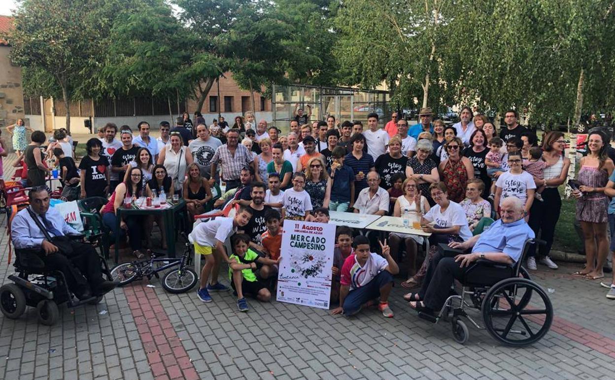 Los vecinos posan con el cartel del Mercado Campesino 2019, que se celebrará el día 11 de agosto. 