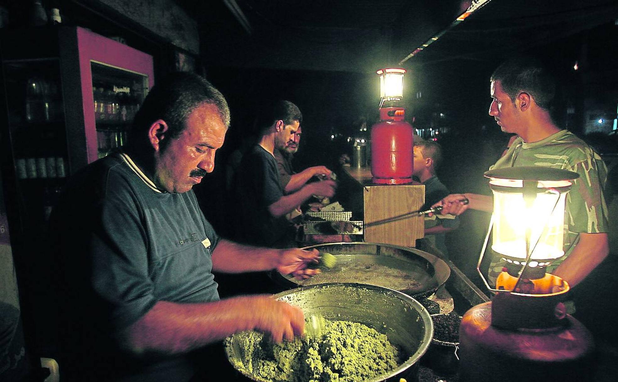 Un hombre prepara falafel a la luz de una linterna de gas en un puesto callejero de la ciudad palestina de Gaza.