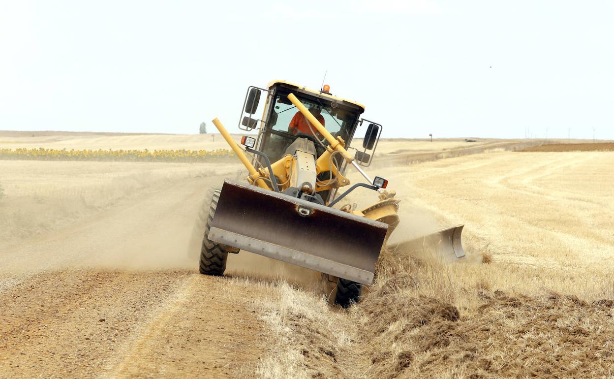 Una motoniveladora limpia la cuneta en uno de los caminos de Autillo de Campos.