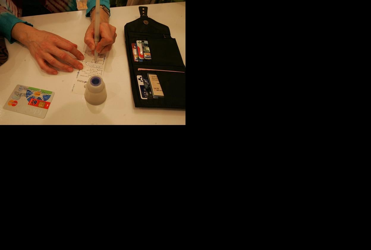 Una mujer firma el recibo de una tarjeta.