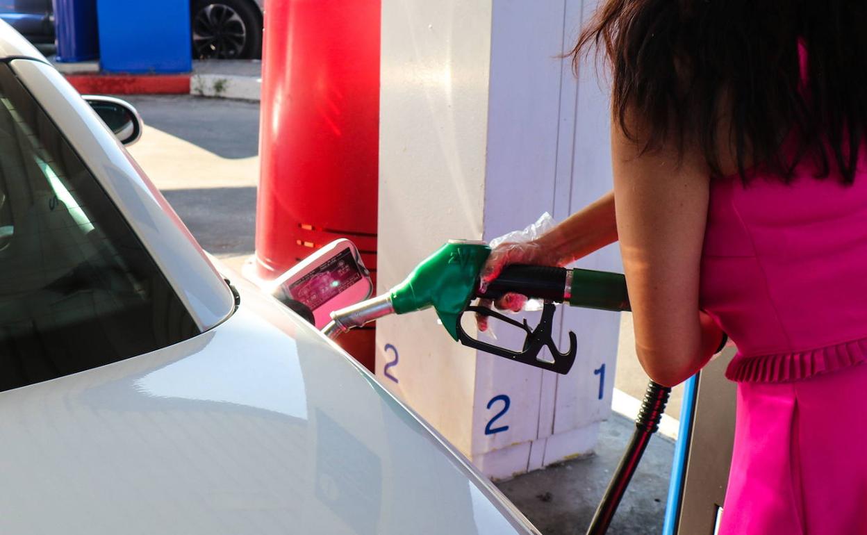Una chica reposta combustible en una gasolinera. 