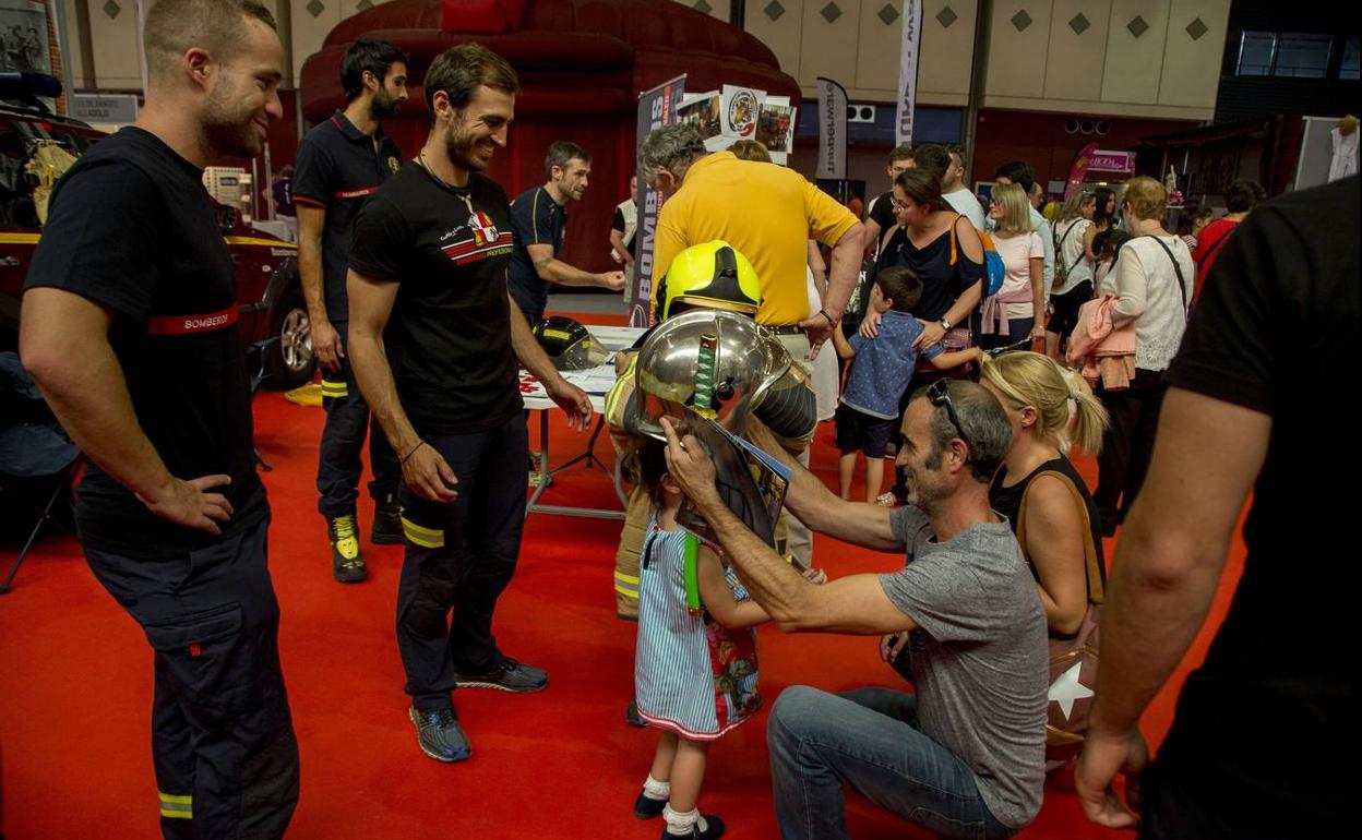 Unos niños se prueban los cascos protectores de los bomberos.