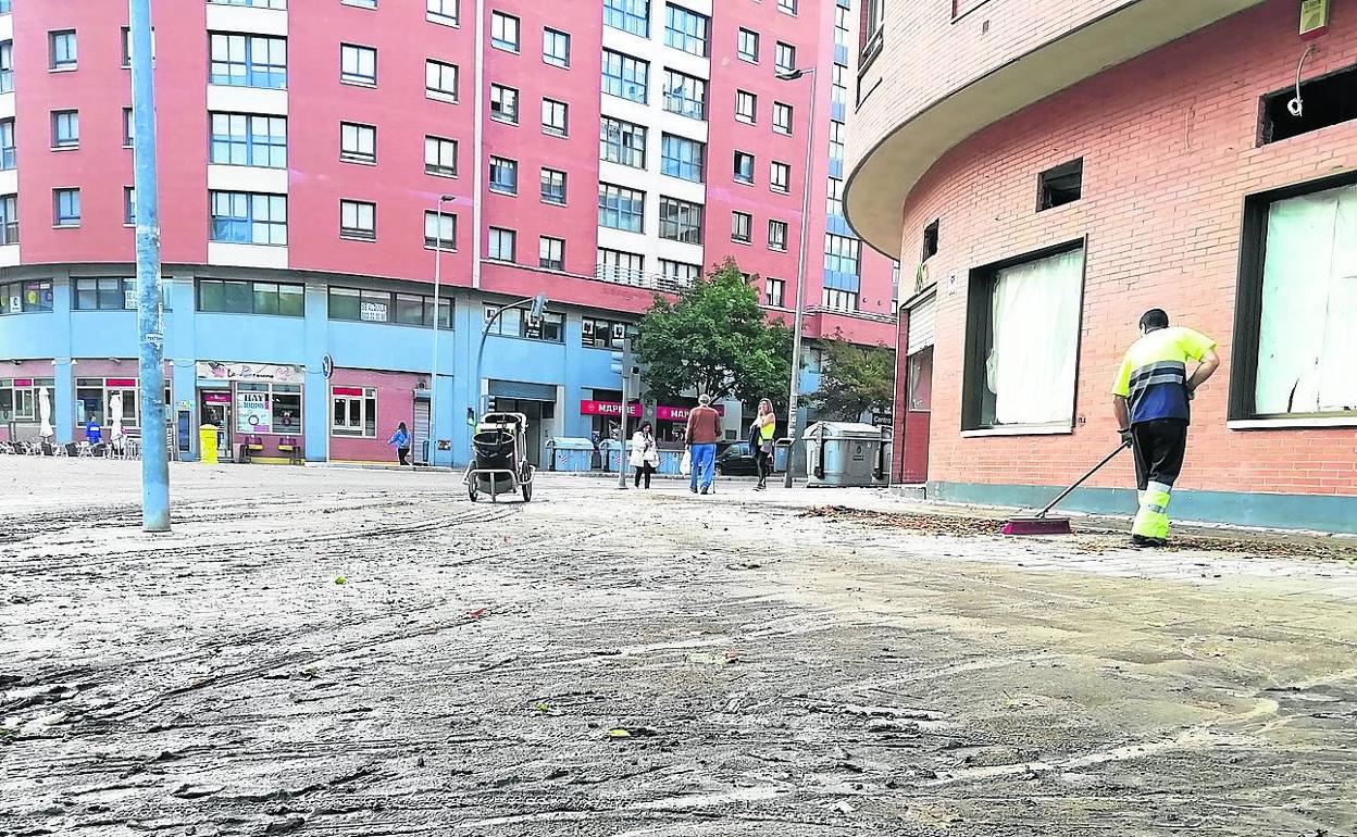 Un operario de Limpieza retira el barro acumulado en la calle Juan García Hortelano (Parquesol). 