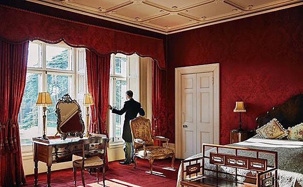 Un mayordomo abre las ventanas de una de las lujosas estancias del inmueble que regentan los condes de Carnarvon..