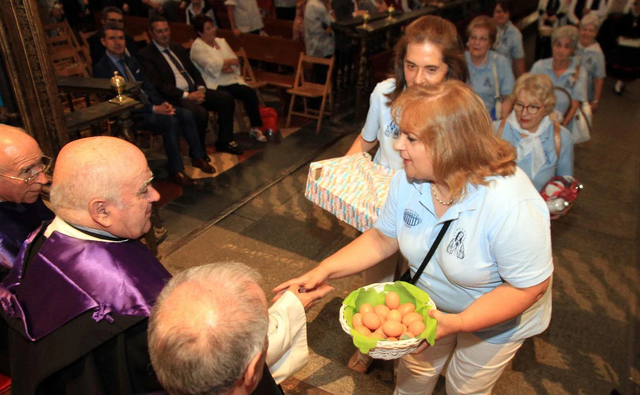 Una mujer entrega una cesta de huevos a los miembros del Cabildo. 