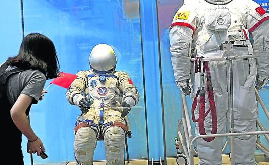 Una visitante observa trajes de astronautas expuestos en Pekín. 