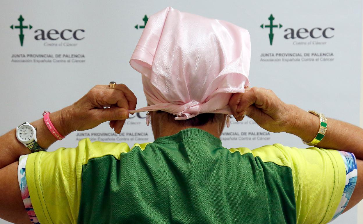 Paula González se anuda un pañuelo rosa en la cabeza en la oficina de la Asociación Española contra el Cáncer.