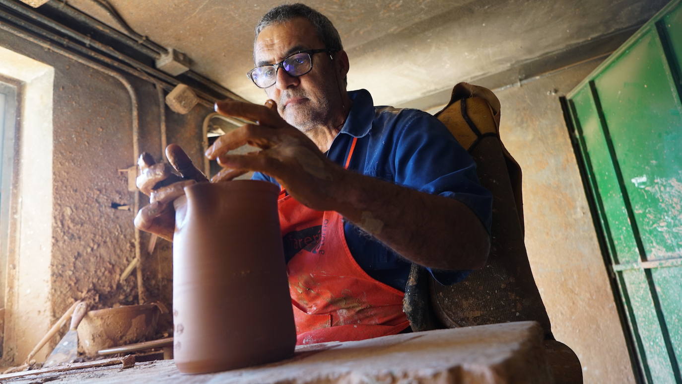 Imagen principal - Javier Velasco (polo azul) y sue hermano Óscar Velasco (camiseta amarilla) trabajan en su taller de Portillo (Valladolid).