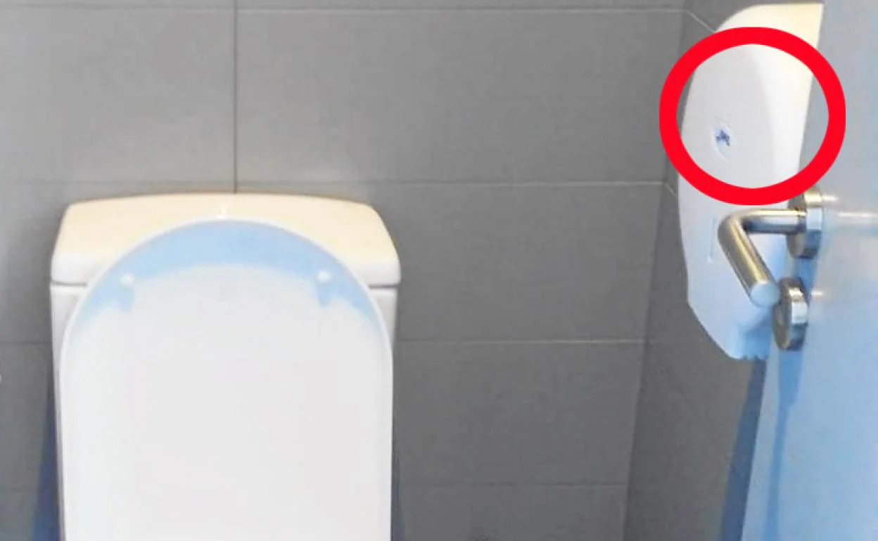 Baño en la sede de la teleoperadora, en cuyo portarrollos de papel higiénico (a la derecha, señalado con un círculo rojo) se encontraba la cámara oculta. 