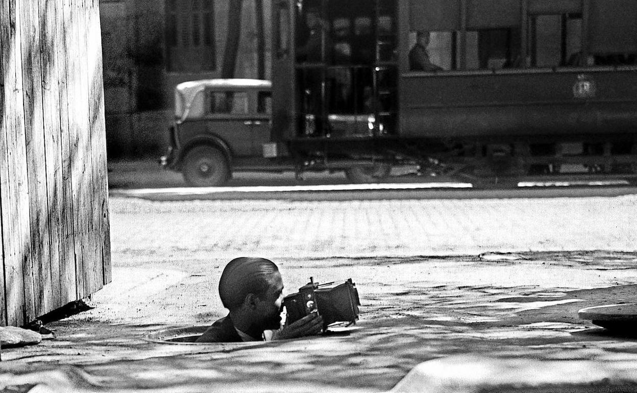 Un fotógrafo saca cabeza y cámara por el agujero de una alcantarilla el 15 de septiembre de 1934 en Madrid.