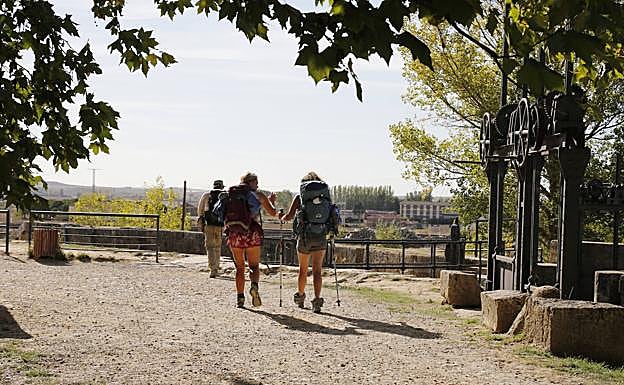 Tres peregrinos atraviesan el Camino de Santiago a su paso por Frómista junto al Canal de Castilla. 