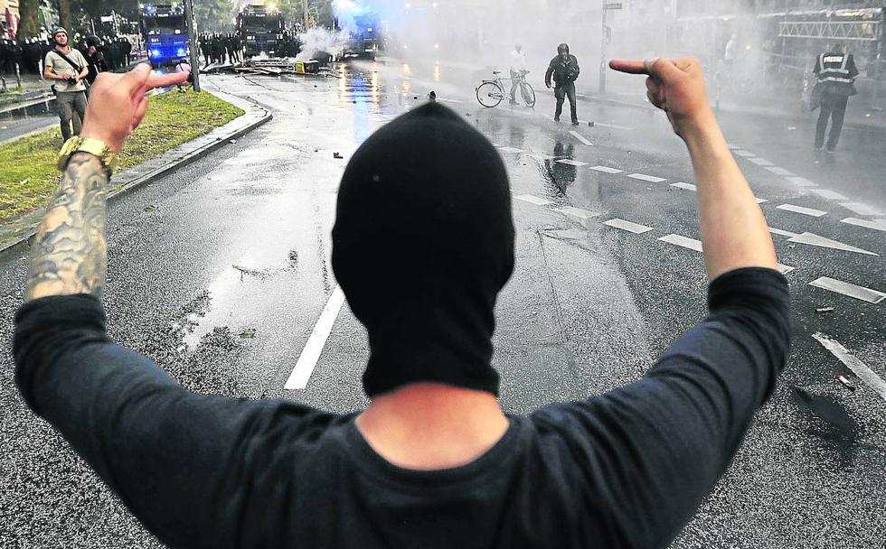 Un joven hace la peineta frente a unos agentes de la Policía en Hamburgo (Alemania.