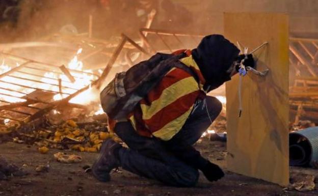 Un manifestante se protege con una plancha de madera durante los disturbios registrados en Barcelona. 